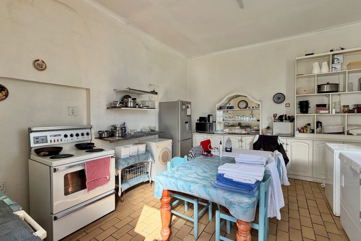A functional kitchen area featuring a freestanding stove, built-in cabinetry, and open shelving, with tiled flooring throughout.