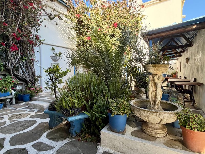 A charming, rustic outdoor patio area featuring stone paving, a decorative fountain, and a covered seating space, ideal for guest relaxation.