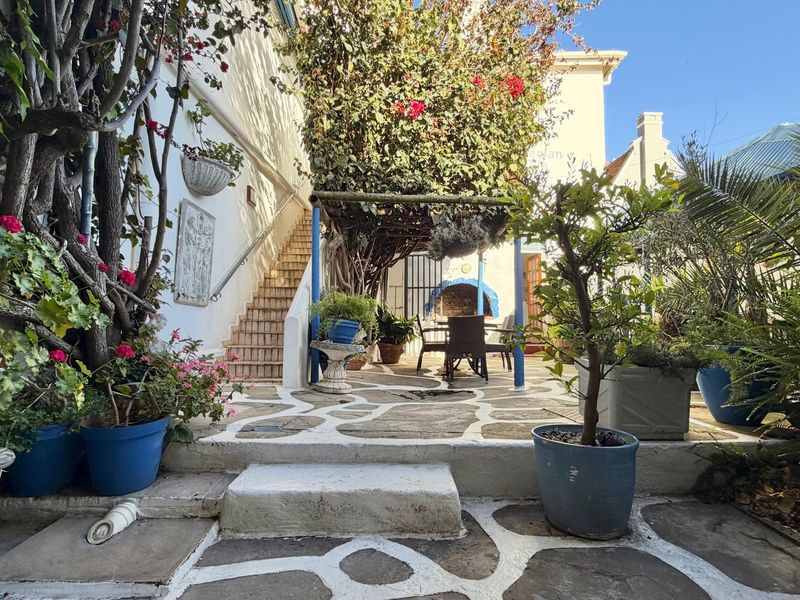 A charming outdoor patio area featuring stone paving, a built-in fireplace, and an external staircase leading to the upper level of the guest house.