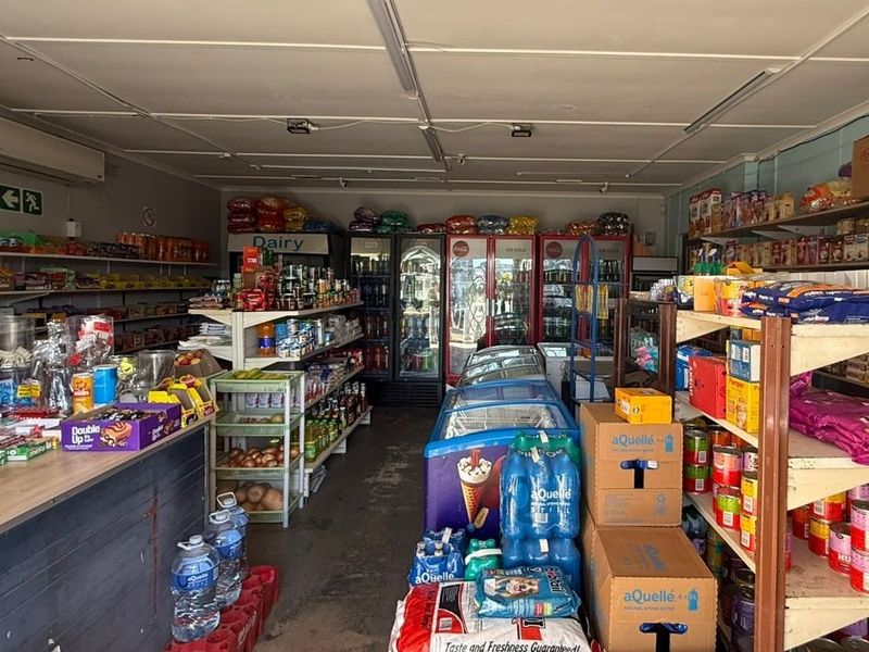 Interior view of a retail convenience store featuring commercial refrigeration units, built-in shelving, and functional lighting throughout the space.