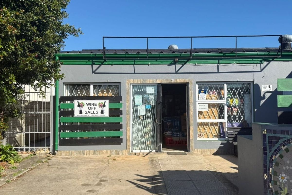 Front facade of a commercial retail unit featuring security gates, security bars on windows, and a paved entrance area.