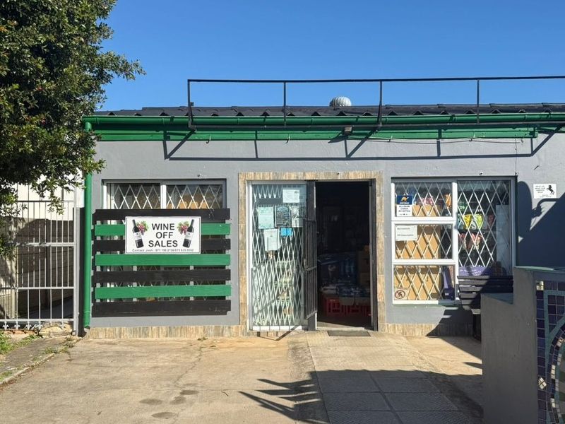Front facade of a commercial retail unit featuring security gates, security bars on windows, and a paved entrance area.