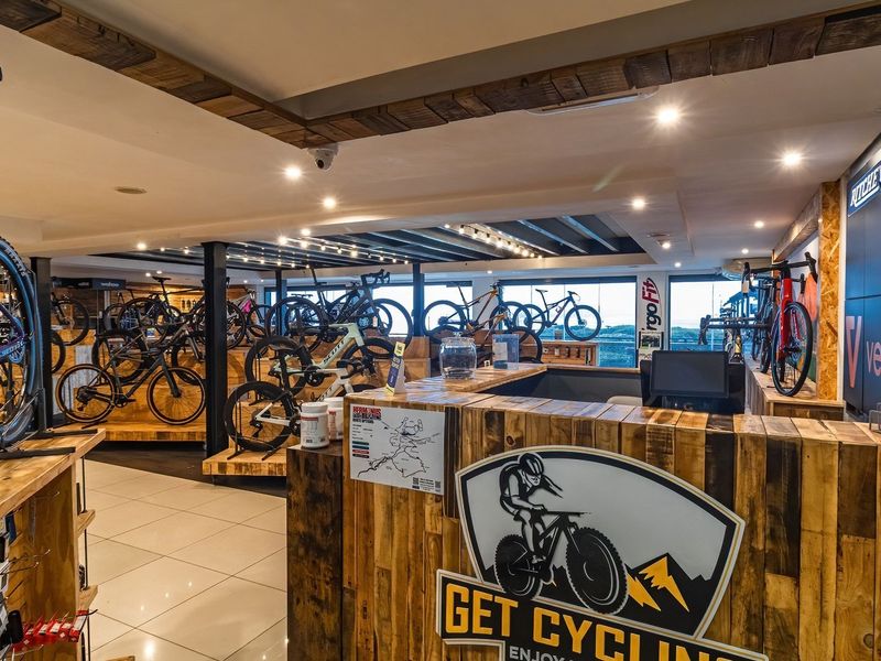 A well-maintained open-plan retail space featuring exposed timber ceiling beams, recessed lighting, tiled flooring, and a custom-built timber service counter.