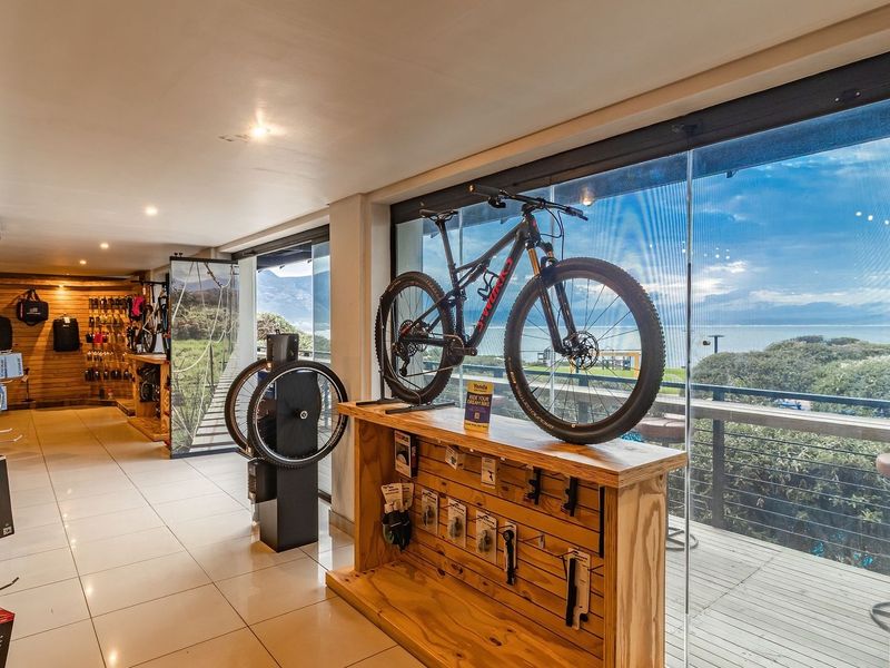 A well-lit retail space featuring tiled floors, timber wall accents, and large glass sliding doors providing scenic outdoor views and balcony access.