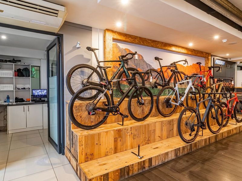 A well-maintained retail display area featuring a custom timber tiered platform for bicycle exhibition, adjacent to a partitioned office or storage space.