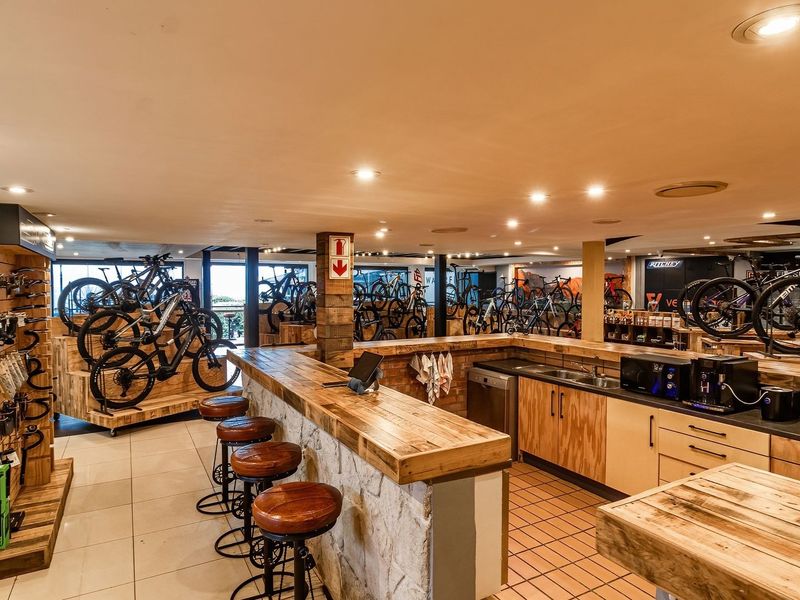 Spacious open-plan retail area featuring a custom timber-topped service counter, built-in cabinetry, recessed lighting, and durable tiled flooring throughout.