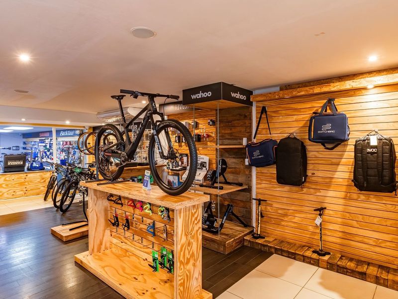 A commercial retail space featuring timber slat wall displays, recessed lighting, and durable flooring, currently configured for bicycle and accessory sales.