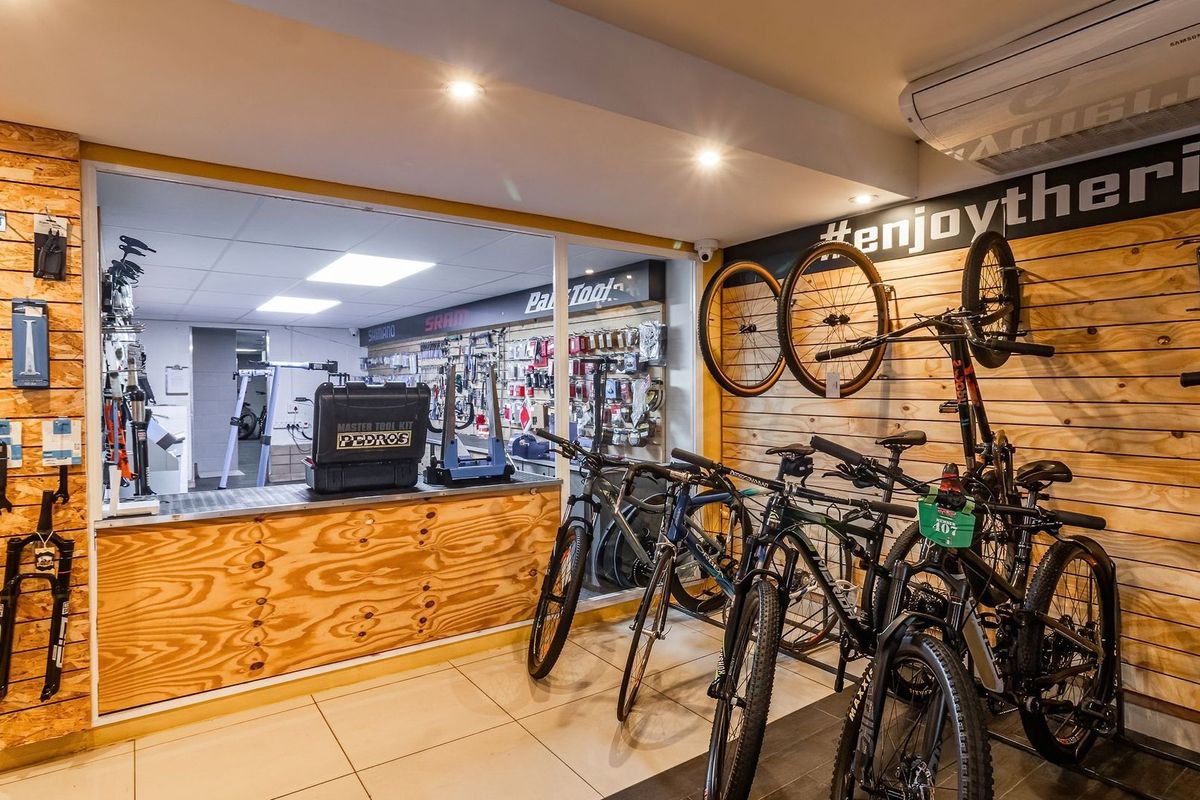 A well-maintained bicycle workshop and retail space featuring plywood wall cladding, tiled floors, recessed lighting, and a dedicated service counter area.