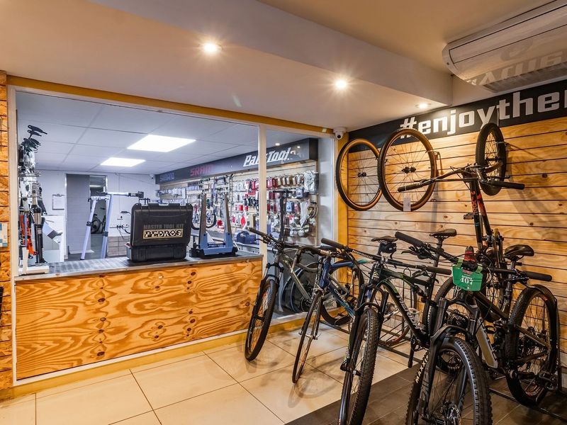 A well-maintained bicycle workshop and retail space featuring plywood wall cladding, tiled floors, recessed lighting, and a dedicated service counter area.