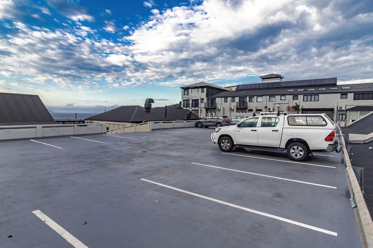 An elevated outdoor parking area featuring marked bays with views of the surrounding building complex and horizon.