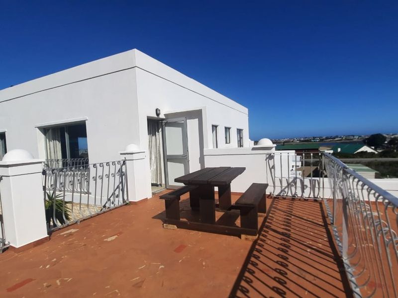Spacious rooftop balcony featuring wrought iron railings and terracotta tiling, offering an open-air space with coastal views.