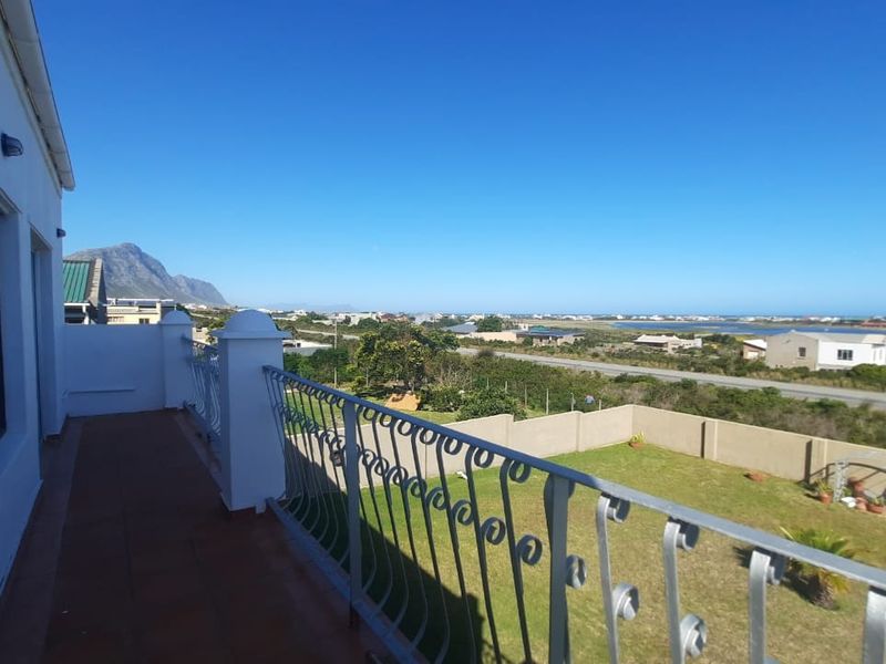 Spacious balcony featuring a wrought iron balustrade and tiled flooring, offering expansive views of the surrounding landscape and coastline.