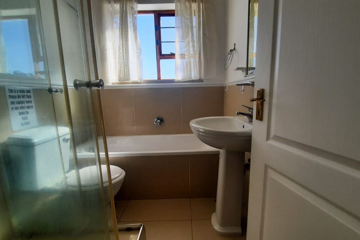 A functional bathroom featuring a pedestal basin, bathtub, and separate shower enclosure with tiled finishes and natural light.