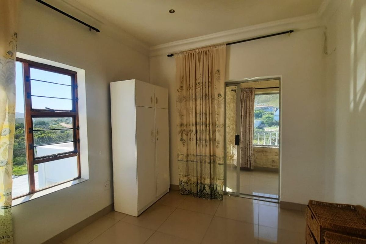 A bright bedroom featuring tiled flooring, a built-in wardrobe, and a sliding glass door providing access to an outdoor balcony area.