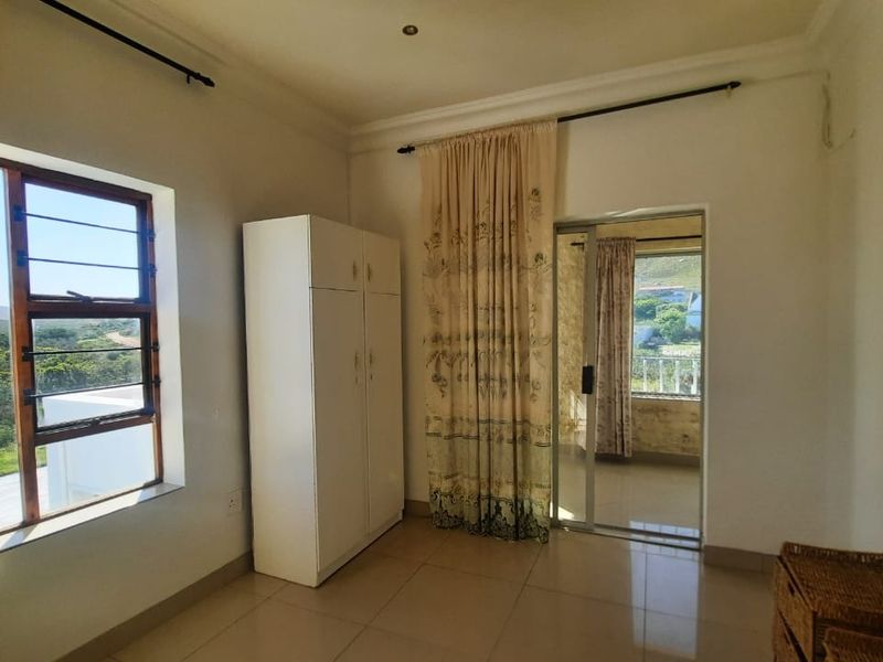 A bright bedroom featuring tiled flooring, a built-in wardrobe, and a sliding glass door providing access to an outdoor balcony area.