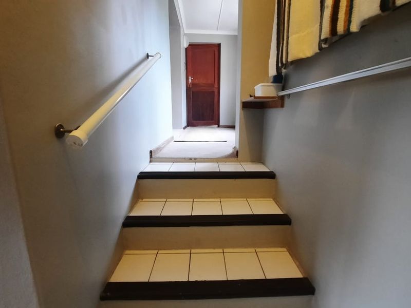 A functional hallway featuring a tiled staircase with a handrail, leading to an interior doorway.