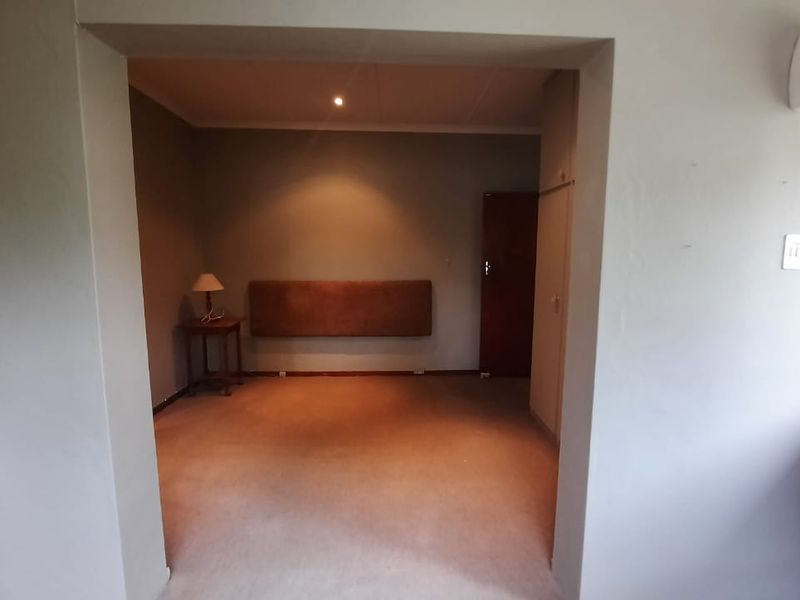 A spacious bedroom featuring neutral walls, built-in cupboard storage, and recessed ceiling lighting, offering a blank canvas for personalization.