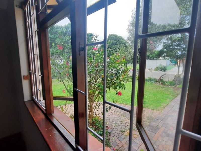 A view from an interior room looking out through timber-framed windows with security bars onto a private garden area.