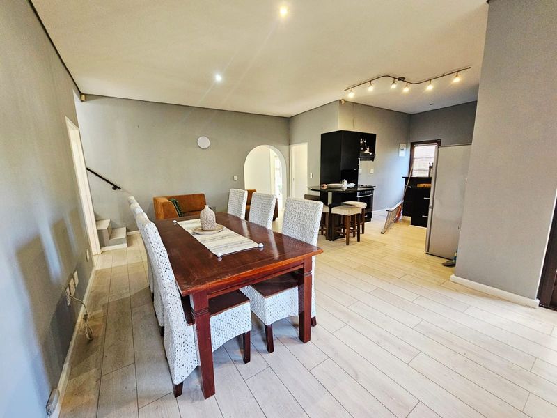 Open-plan living and dining area featuring tiled flooring, recessed lighting, and an arched transition to the kitchen space.