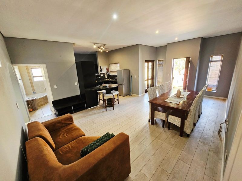 Spacious open-plan living and dining area featuring tiled floors, recessed lighting, and a functional kitchen with a central island.
