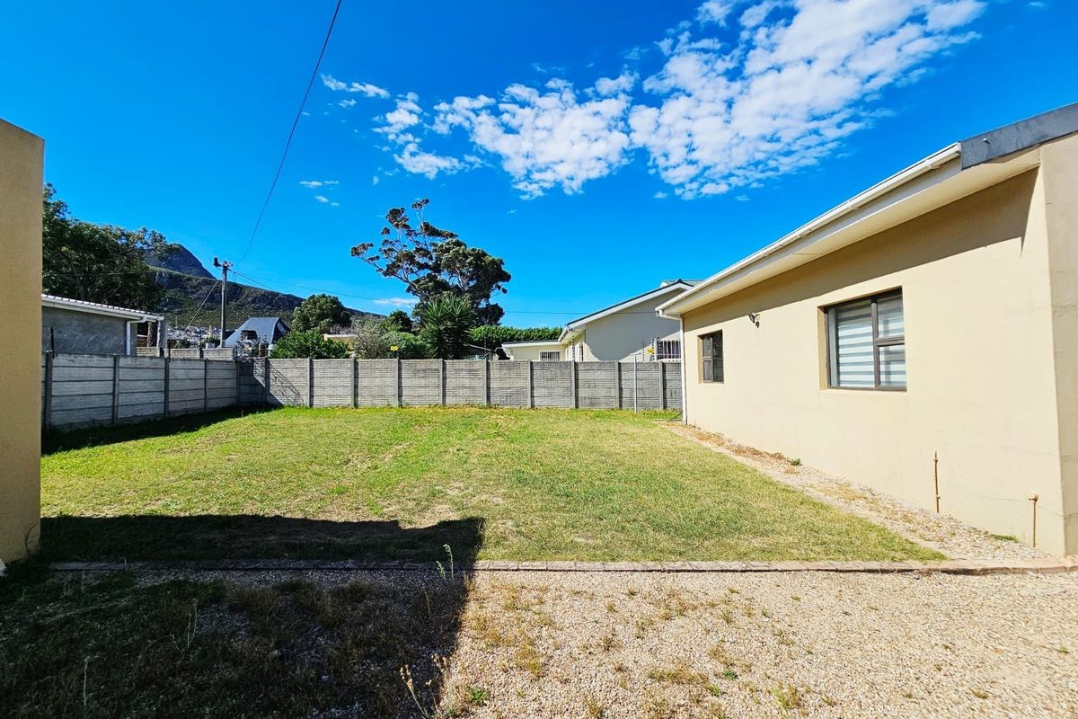 A spacious rear garden featuring a lawn area, gravel section, and secure precast concrete boundary walling.