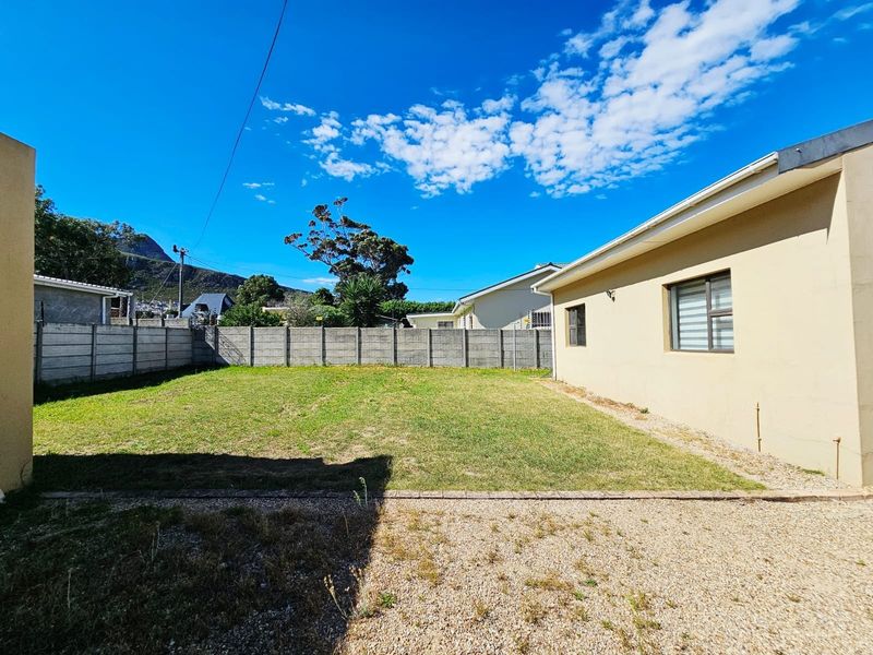 A spacious rear garden featuring a lawn area, gravel section, and secure precast concrete boundary walling.