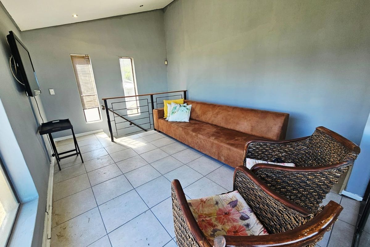 A living area featuring tiled flooring, a metal balustrade, and vertical windows, providing a functional space with neutral wall finishes.