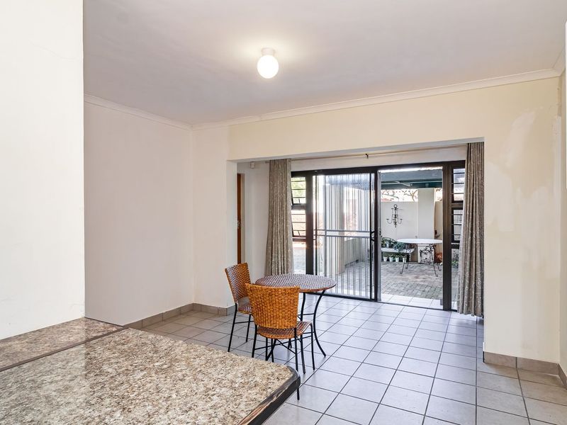 Open plan living area featuring tiled flooring, a granite breakfast counter, and sliding glass doors providing direct access to an outdoor patio space.