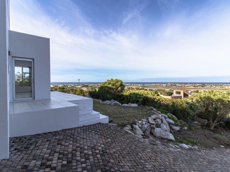 A clean, tiled patio area offering expansive coastal and landscape views, featuring stone paving and a well-maintained exterior structure.