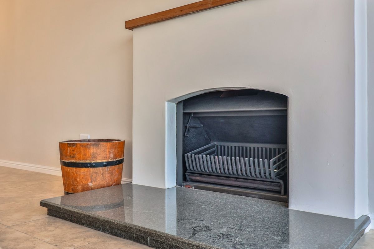 A clean living room space featuring a built-in fireplace with a polished granite hearth and a simple wooden mantelpiece.