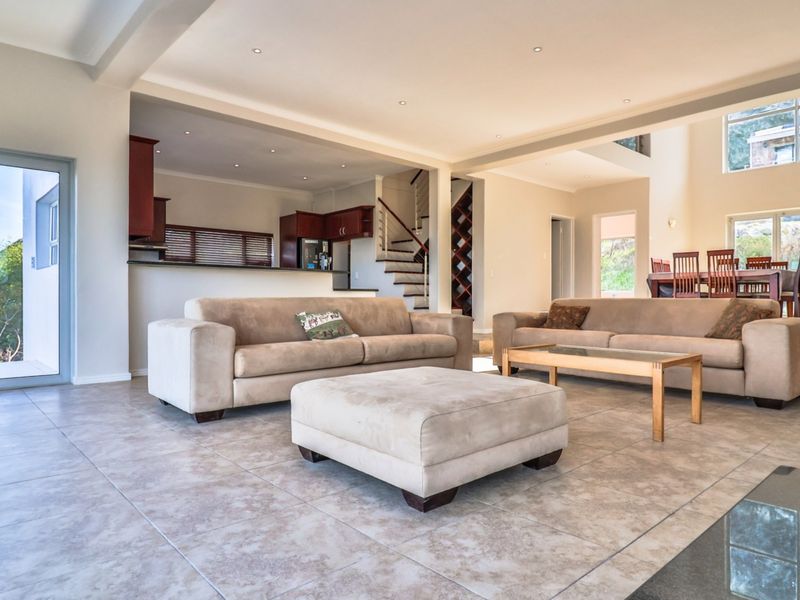 Spacious open-plan living area featuring tiled floors, recessed lighting, a modern kitchen with breakfast counter, and a feature staircase with built-in wine storage.
