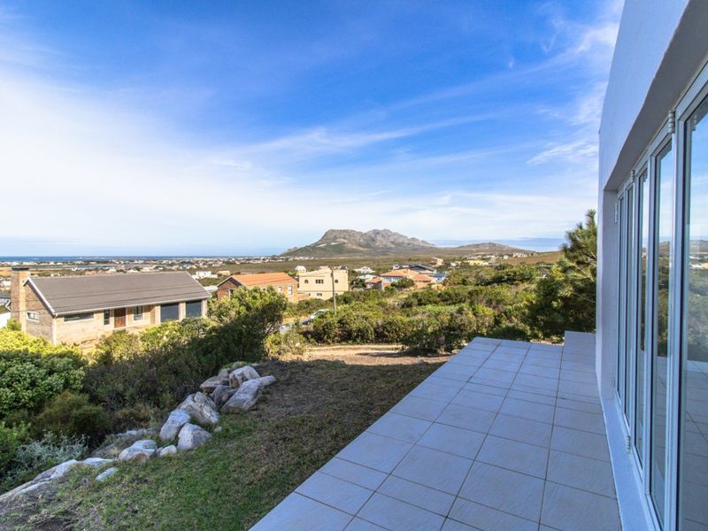 Elevated view from a tiled patio overlooking the surrounding neighbourhood, coastal landscape, and distant mountains.