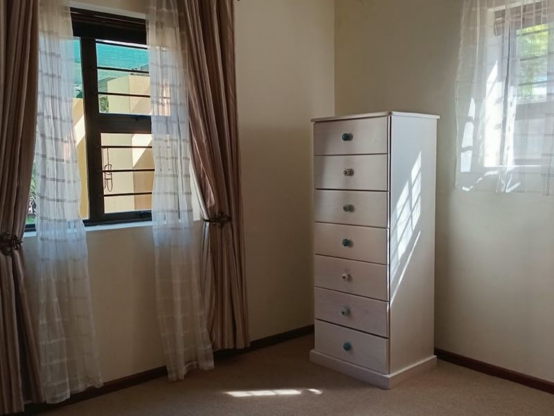 A bedroom featuring carpeted flooring, neutral walls, and windows fitted with security burglar bars.