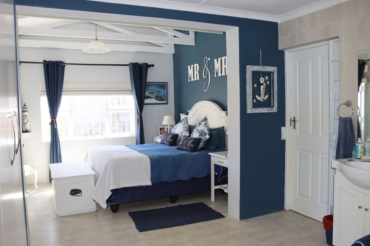 A bedroom featuring exposed ceiling beams, tiled flooring, and an integrated vanity area with a sink.