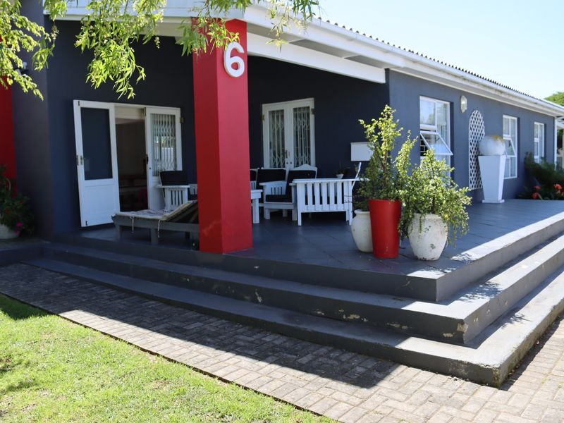 A covered patio area featuring tiled flooring, concrete steps, and direct access to the interior through french doors with security gates.