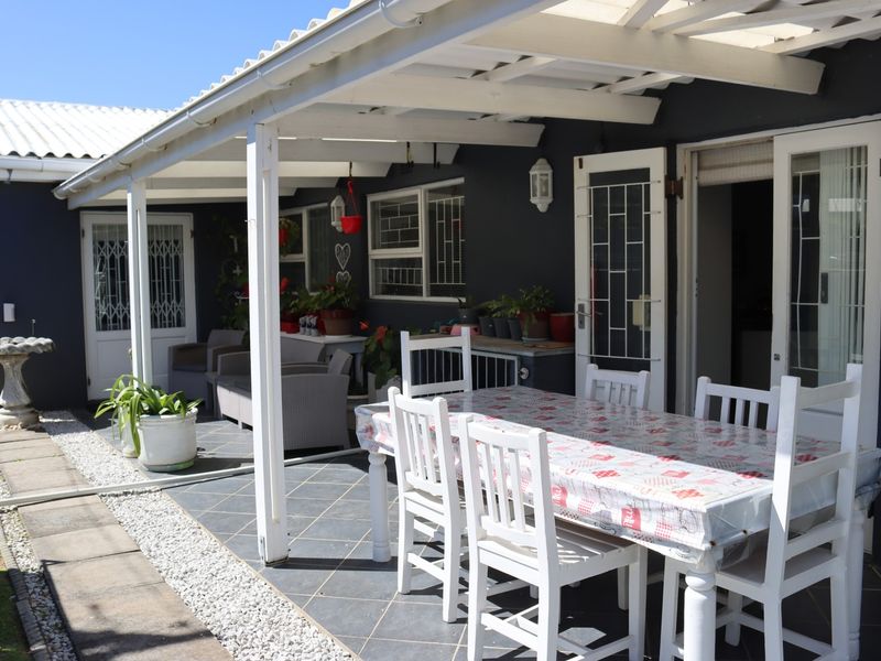 A covered outdoor patio area featuring tiled flooring and a white timber pergola, providing a functional space for outdoor dining and relaxation.