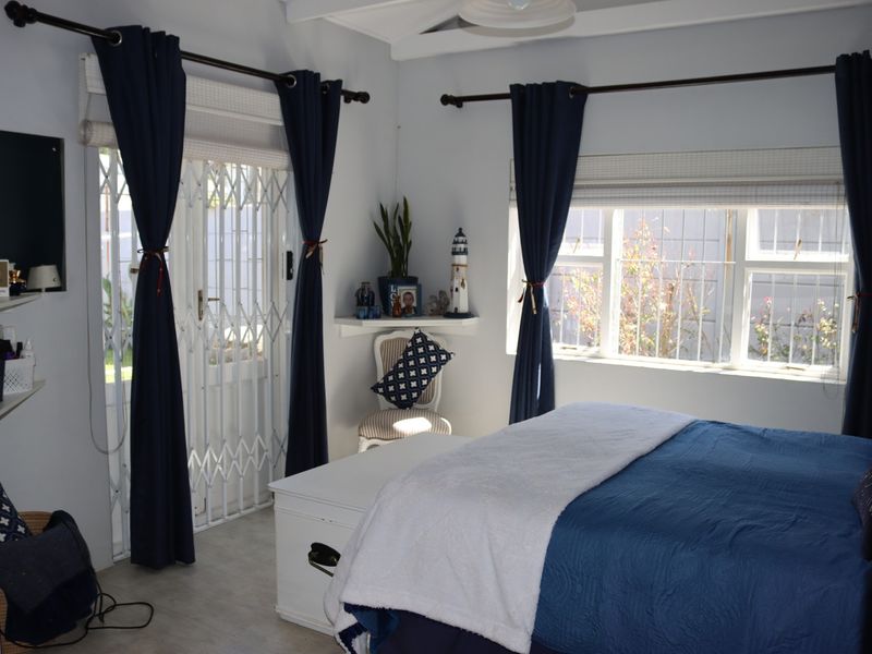 A well-lit bedroom featuring exposed ceiling beams, a security gate leading to the exterior, and a built-in corner shelf.
