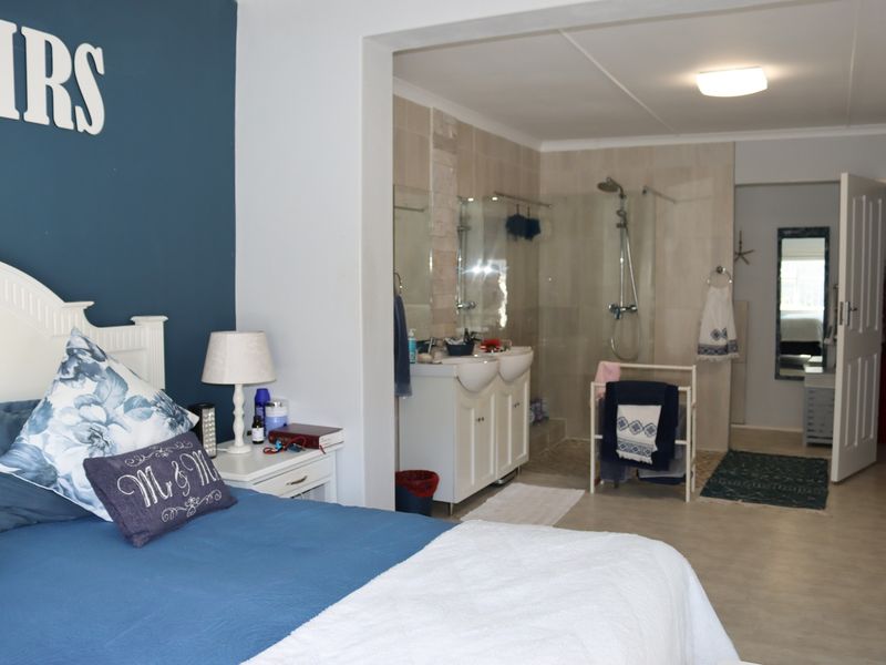 Spacious bedroom featuring an open-plan en-suite bathroom with a double vanity and a modern glass-enclosed shower.