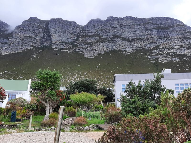 A scenic view of the property featuring a well-maintained garden set against a dramatic mountain backdrop.