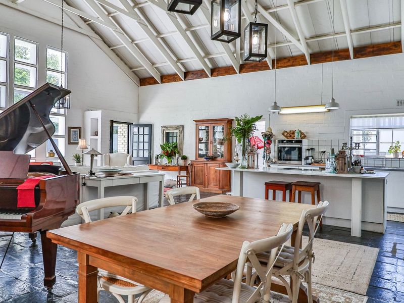 Spacious open-plan living and kitchen area featuring a high vaulted ceiling with exposed timber beams, tiled flooring, and a functional kitchen island.