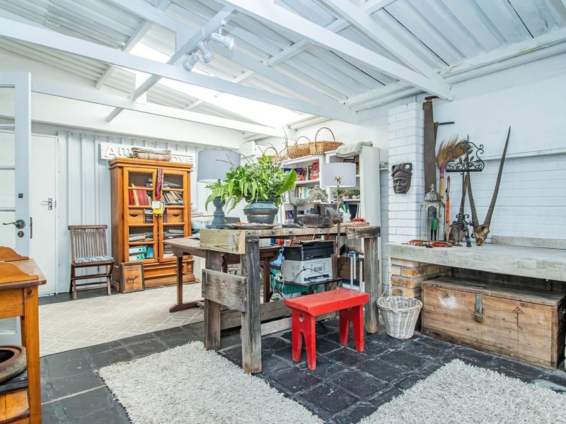 A rustic covered patio area featuring exposed white-painted beams, a brick fireplace with a concrete hearth, and dark slate tile flooring.