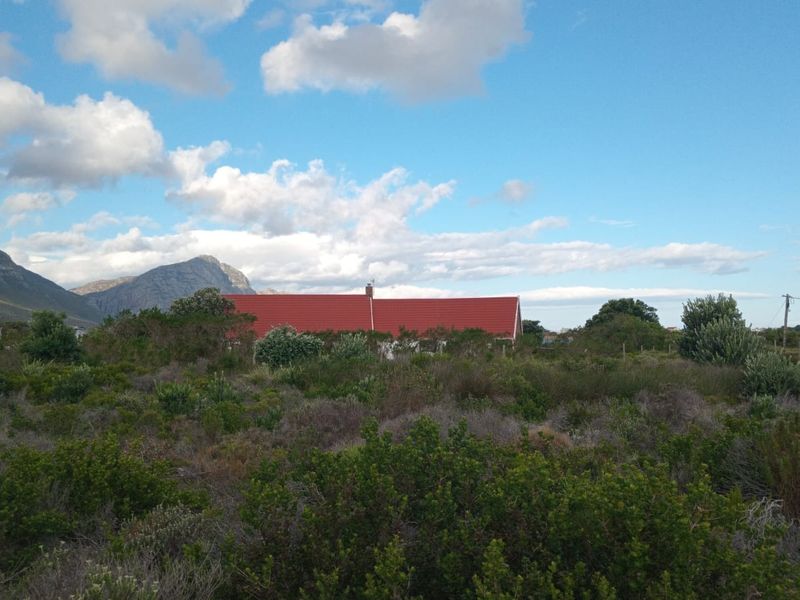 A view of a residential property with a red pitched roof, set against a backdrop of mountains and natural vegetation.
