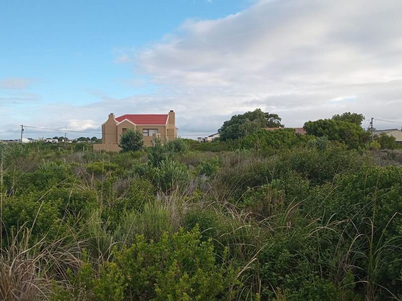 A view of a vacant residential plot featuring natural coastal vegetation and surrounding neighborhood properties.