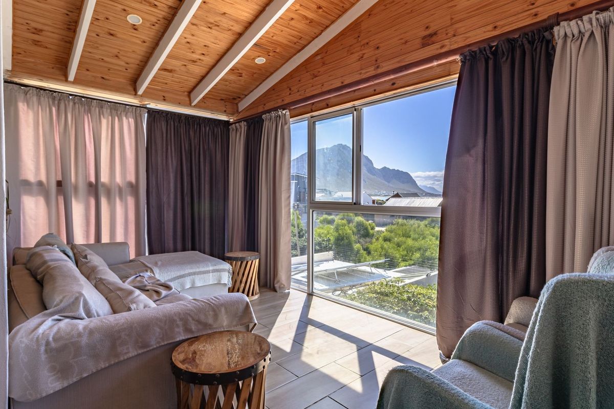 A bright living area featuring a vaulted timber ceiling, large glass sliding doors, and scenic mountain views.