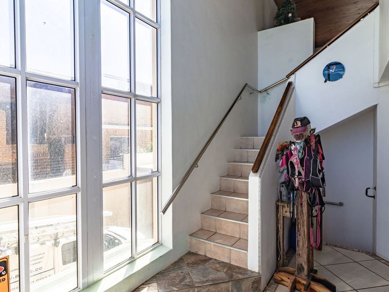 Entrance foyer featuring a tiled staircase with a stainless steel handrail and large windows providing ample natural light.