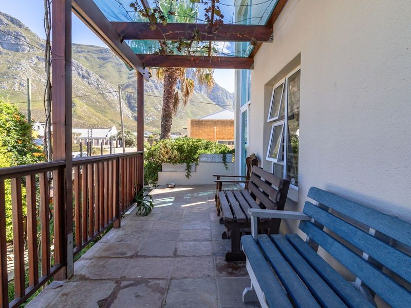 A covered patio area featuring a timber pergola, tiled flooring, and a timber balustrade with mountain views.