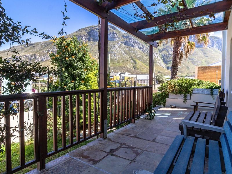 A covered patio featuring a timber pergola, tiled flooring, and a timber balustrade, offering scenic mountain views.