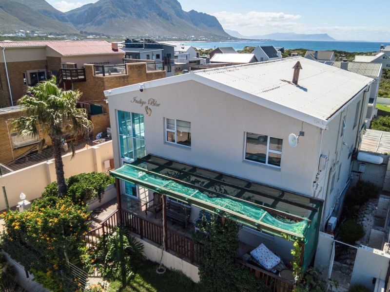 Aerial view of a coastal property featuring a corrugated metal roof, covered patio with timber decking, and secure perimeter fencing.