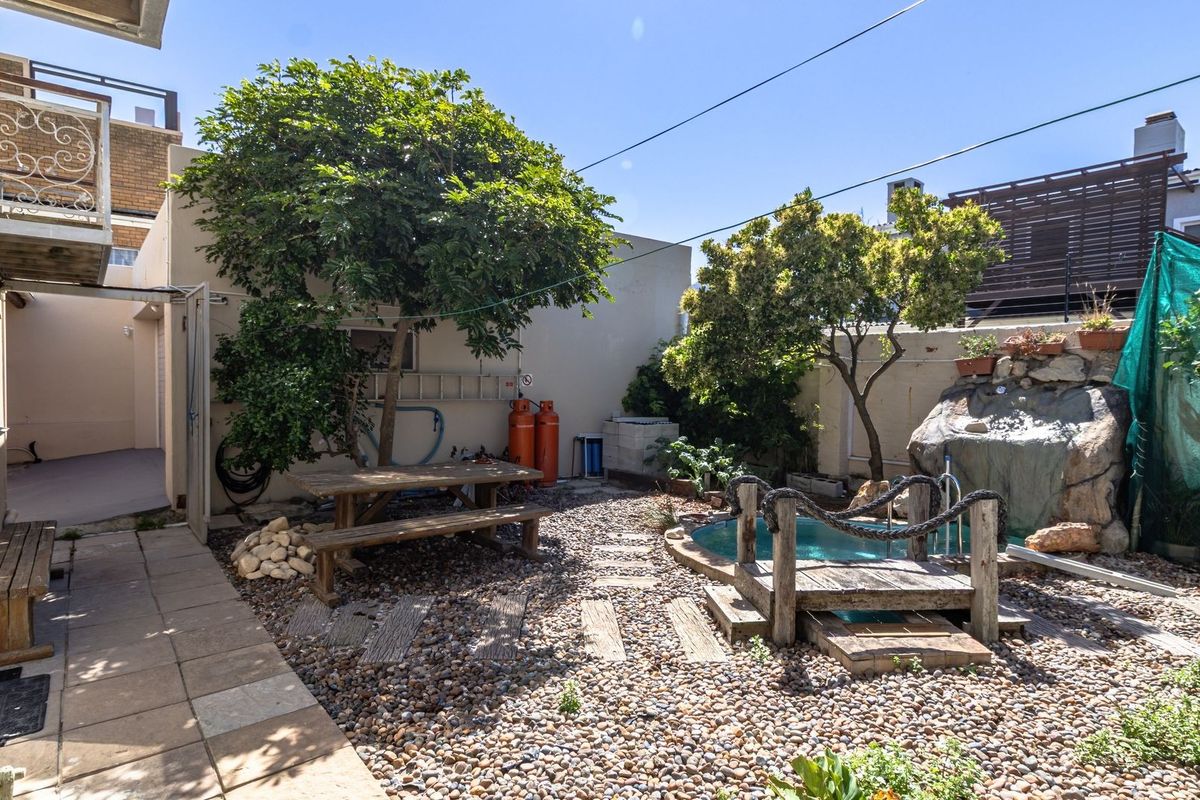 Rear courtyard area featuring a small plunge pool, stone water feature, gravel landscaping, and a paved walkway with access to an upper balcony.