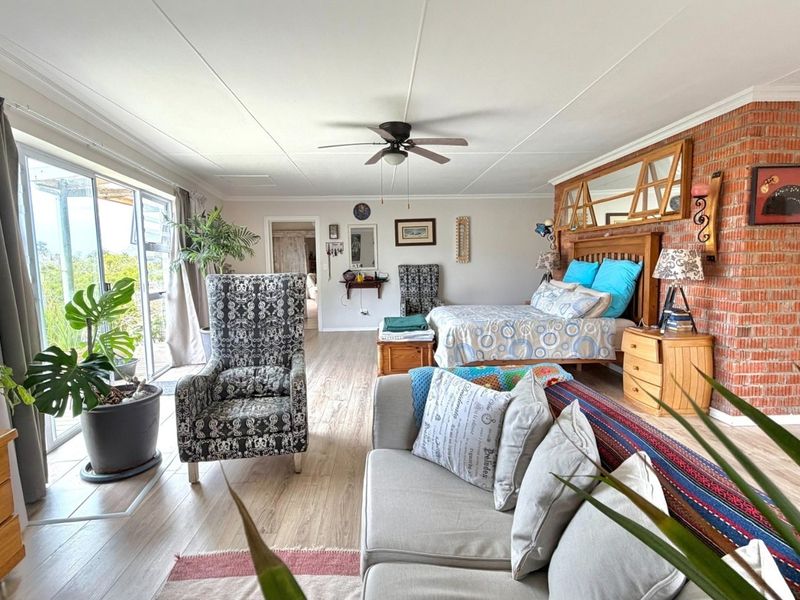 Spacious bedroom featuring exposed brick wall detailing, laminate flooring, and large sliding glass doors providing natural light and access to the exterior.